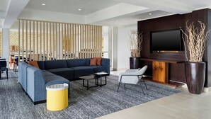 A modern living room with a sectional sofa, a flat-screen TV, a coffee table, and a potted plant.