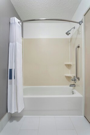 Une salle de bain moderne équipée d’une baignoire, d’une douche et d’une barre d’appui.