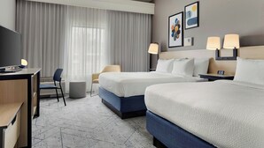 A hotel room with two beds, a desk, a chair, a TV, and a large window with curtains.