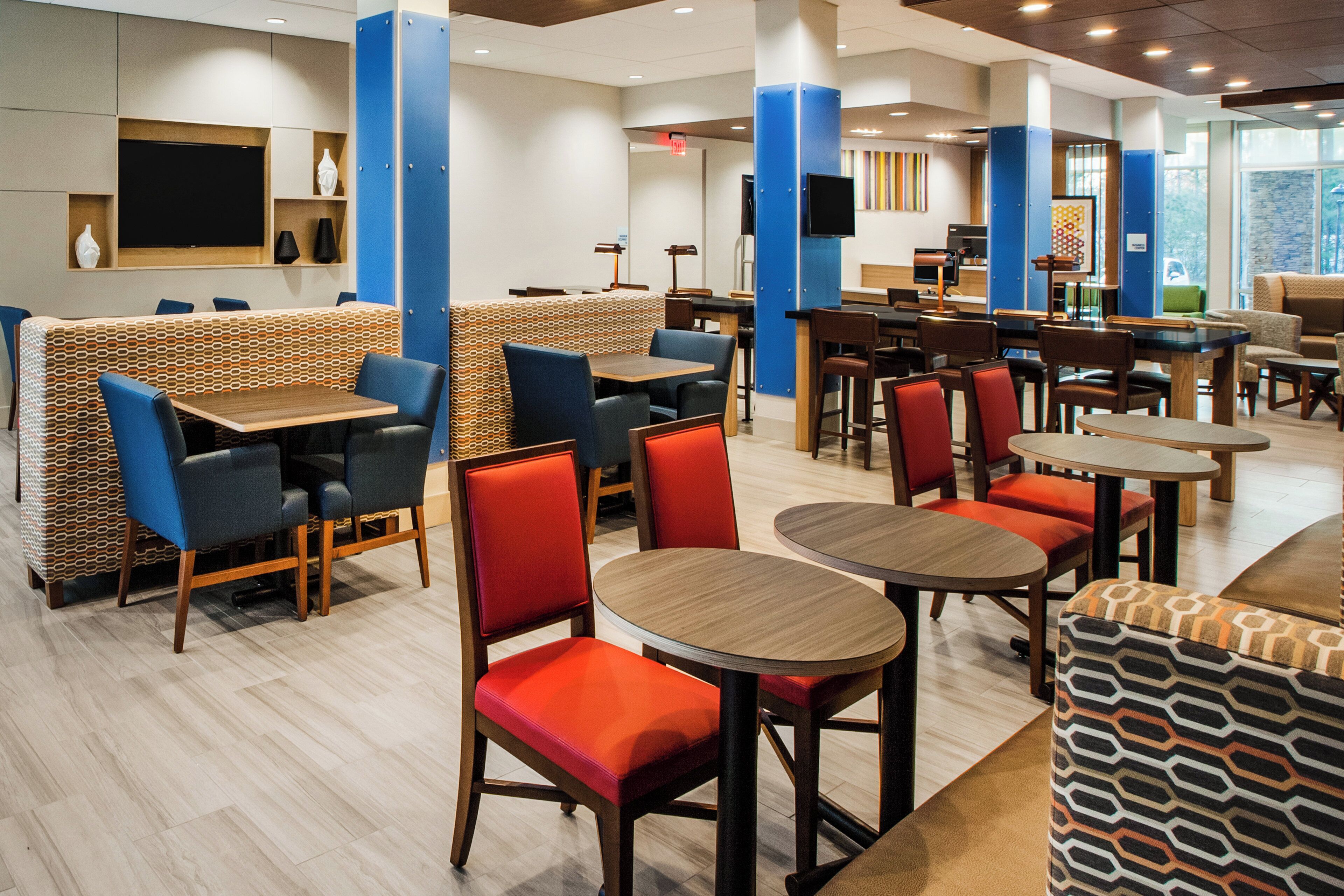 A modern restaurant with booths, round tables, and high chairs.