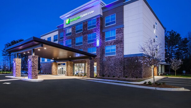 A Holiday Inn Express & Suites building with a modern design, featuring a covered entrance and stone facade.