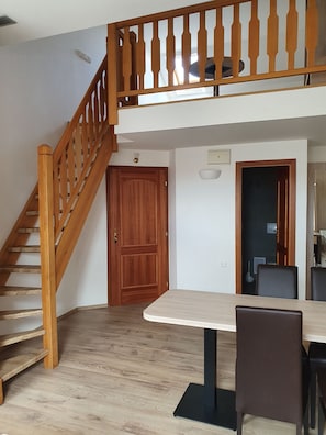 A room with a wooden staircase, a dining table with chairs, and a door leading to another room. - Hotel Residence Select (Prague)