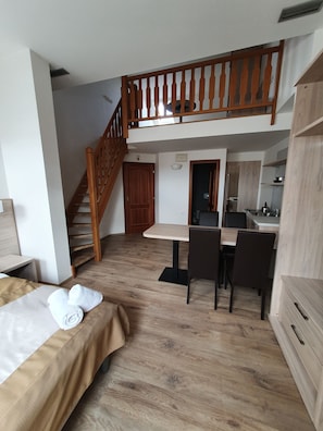 A hotel room with a bed, a wooden staircase, a dining area with a table and chairs, and a kitchenette. - Hotel Residence Select (Prague)