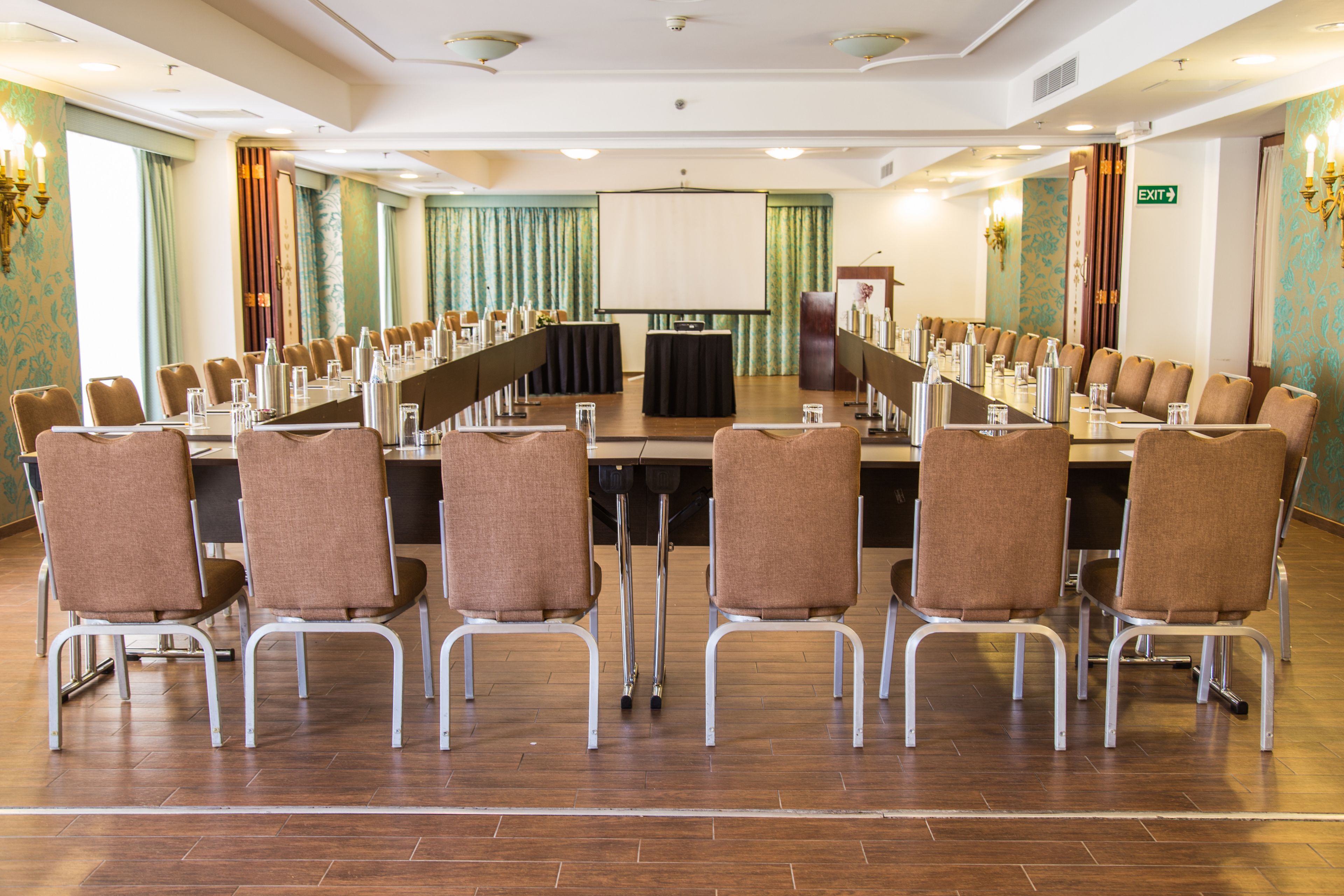 A conference room with a long table, chairs, a projector screen, and a podium.