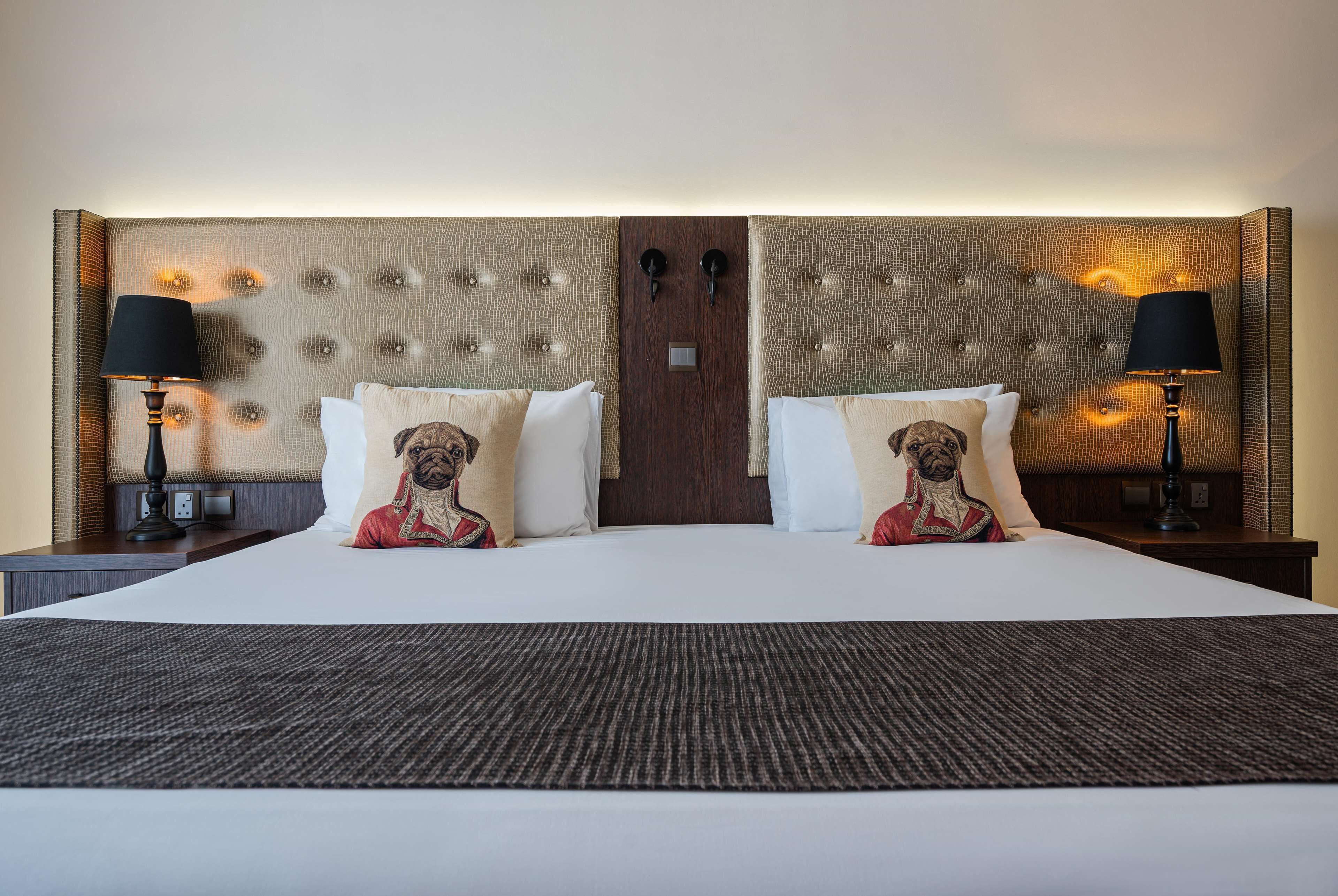 A hotel room with a large bed, two nightstands, and a headboard with a textured design.