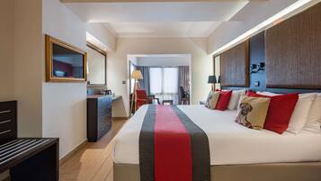 Una habitación de hotel con una cama grande, un escritorio, una silla, un aparador y un espejo.