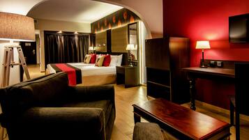 Ein Hotelzimmer mit Bett, Schreibtisch, Stuhl, Fernseher und Lampe.