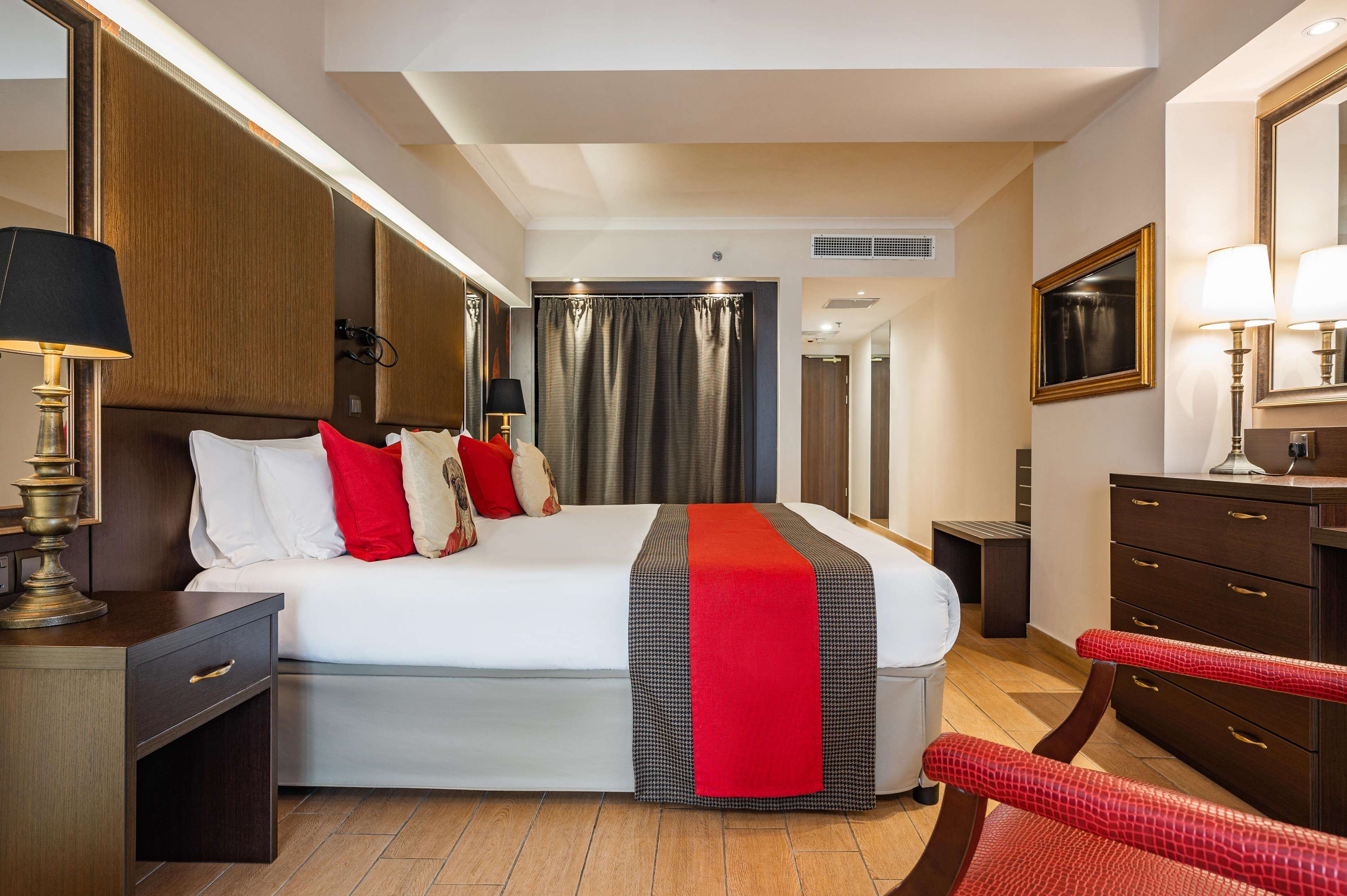 A hotel room with a large bed, bedside tables, a desk, and a chair.