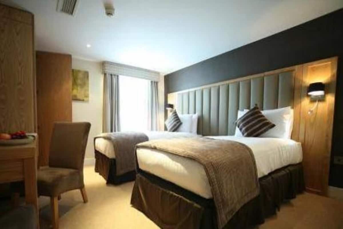 Hotellihuone, jossa on sänky, tuoli, työpöytä ja ikkuna.