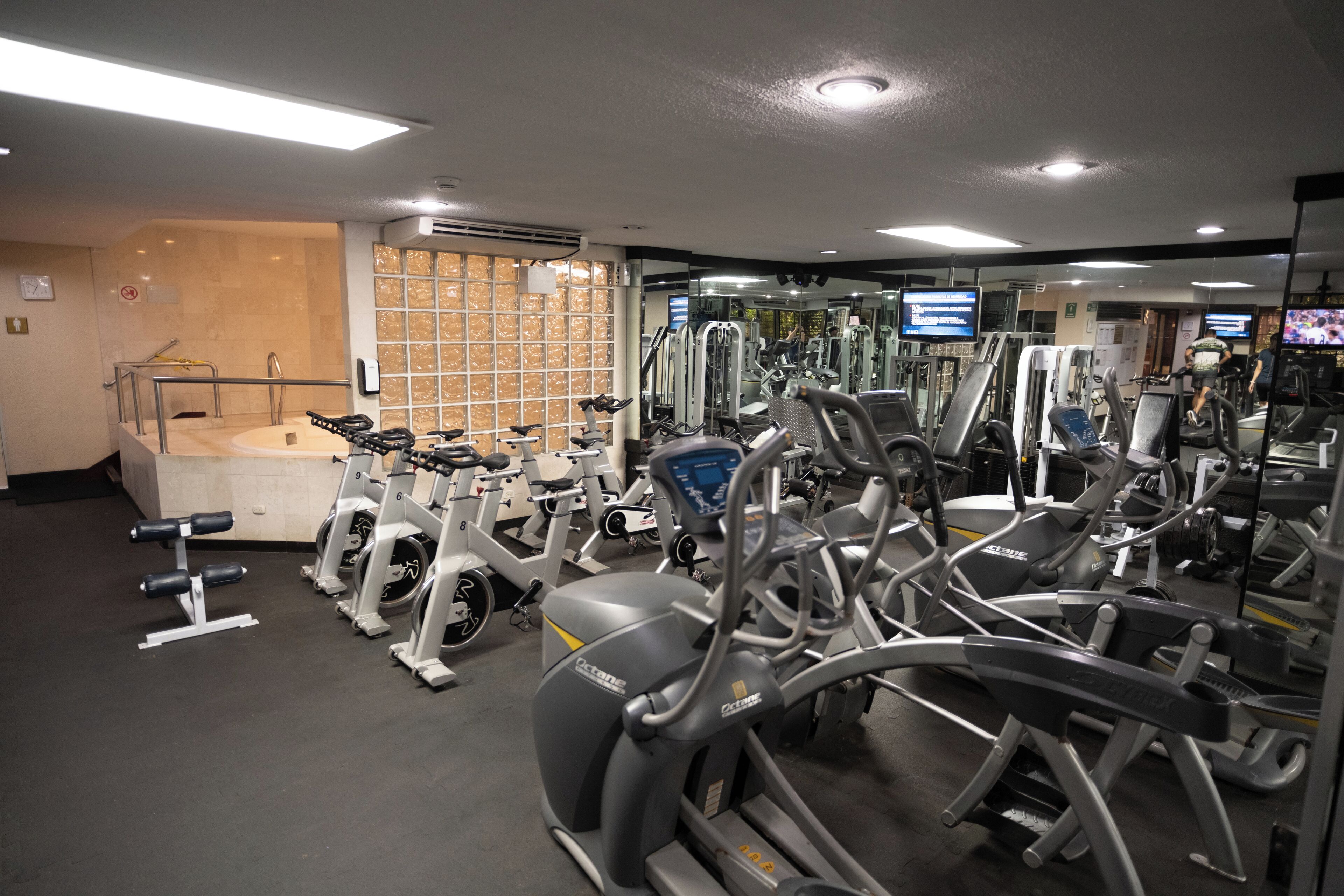 A gym with various exercise equipment, a large mirror, and a wall-mounted TV.