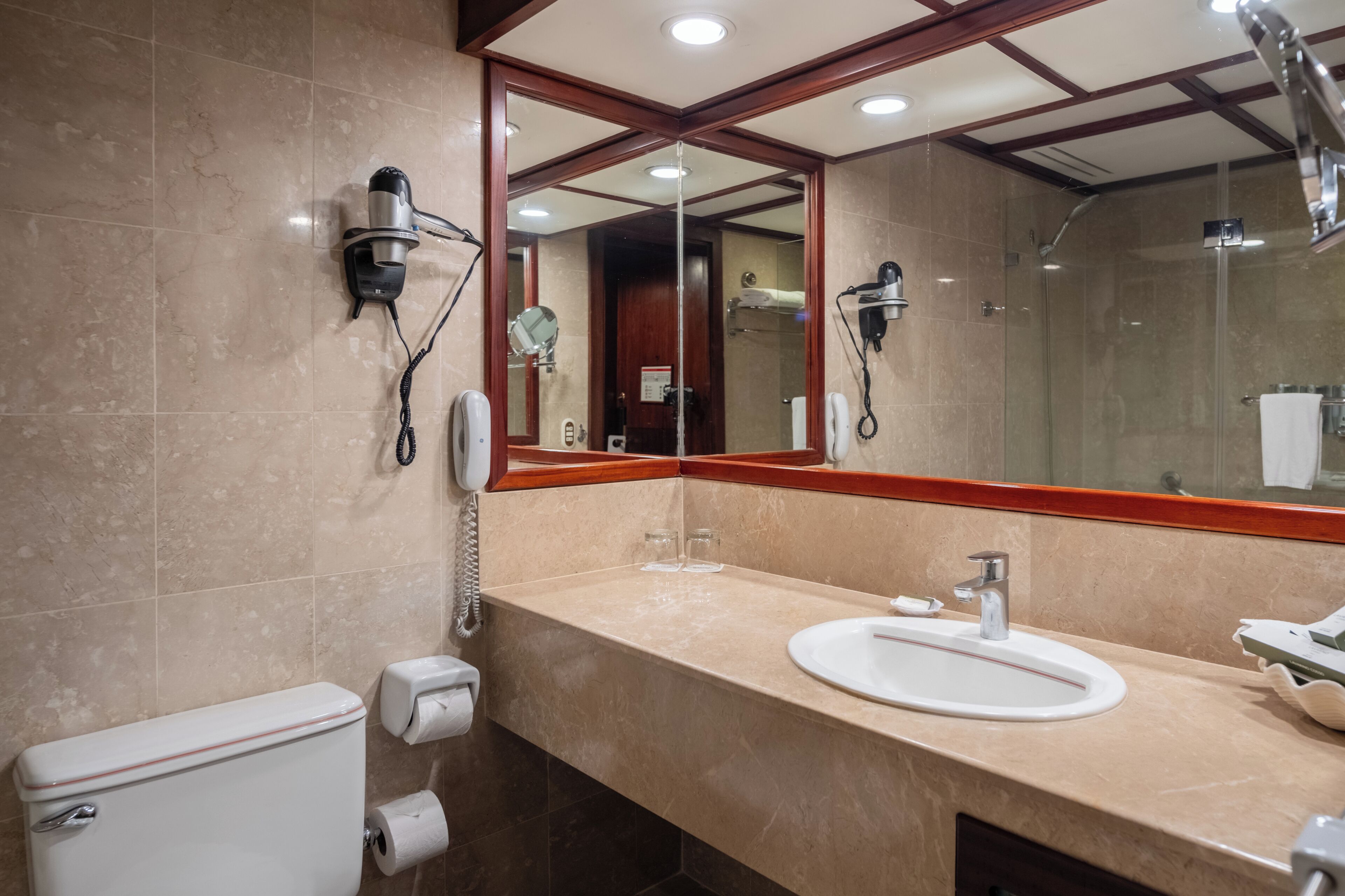 A bathroom with a toilet, sink, mirror, and shower.