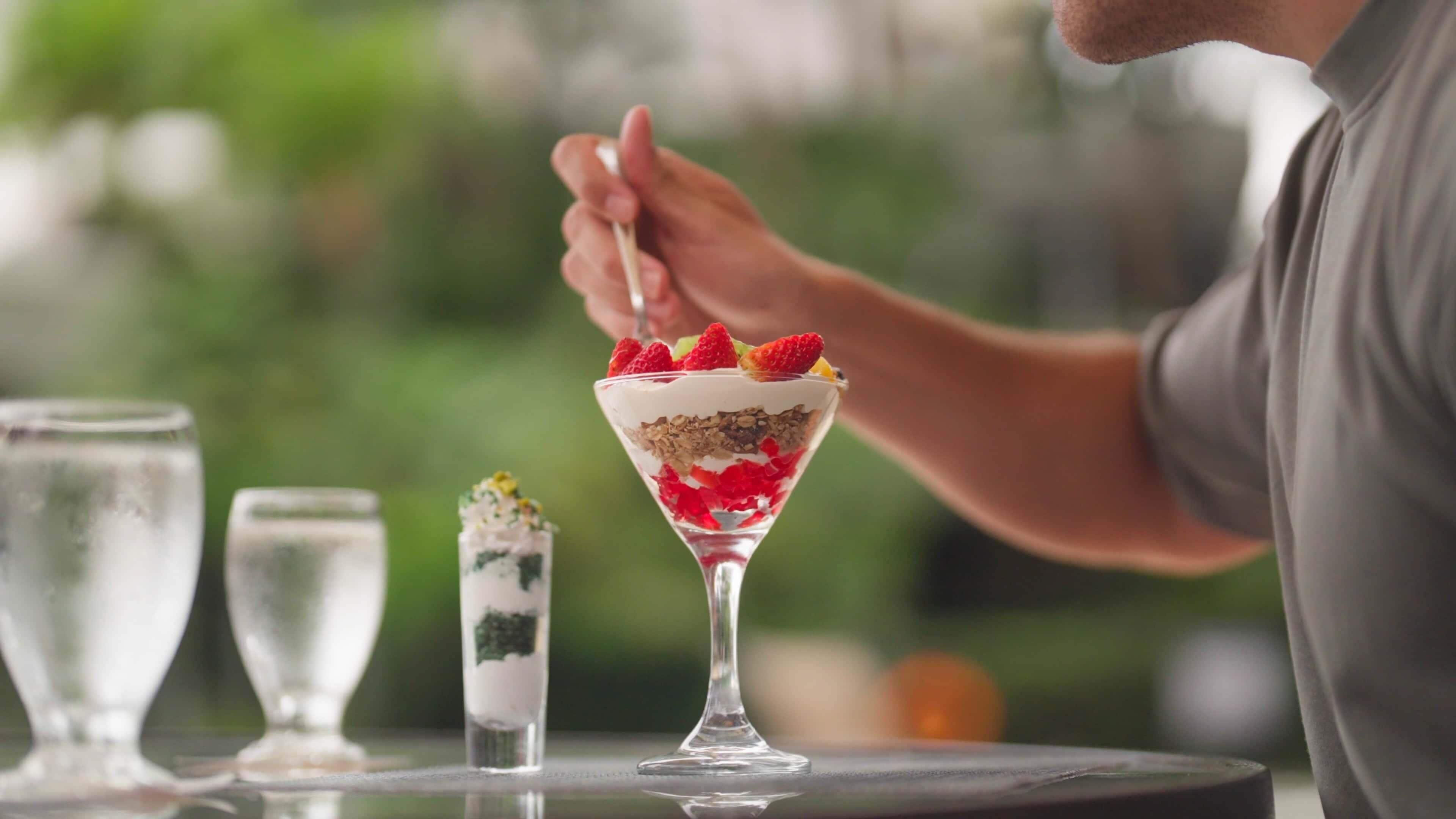 Eine Person serviert ein mehrschichtiges Dessert im Martini-Glas.