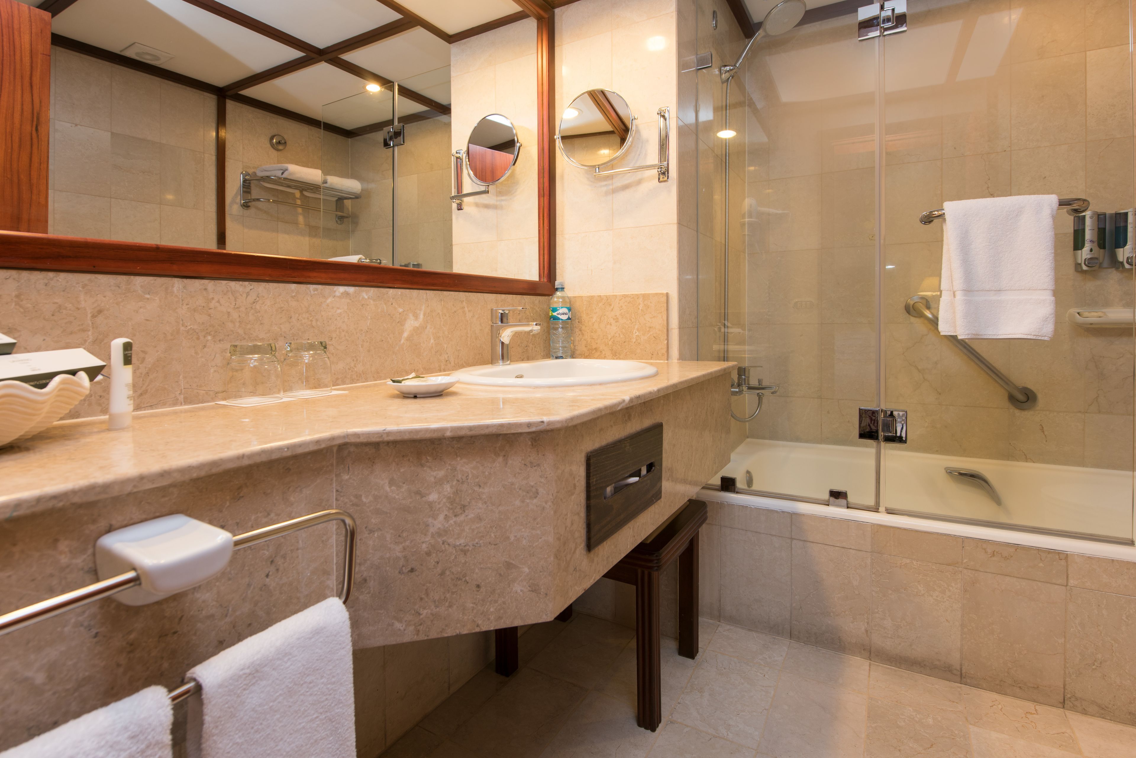 A modern bathroom with a marble sink, a glass-enclosed shower, and a large mirror.