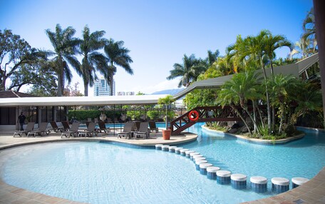 A swimming pool with lounge chairs and palm trees.