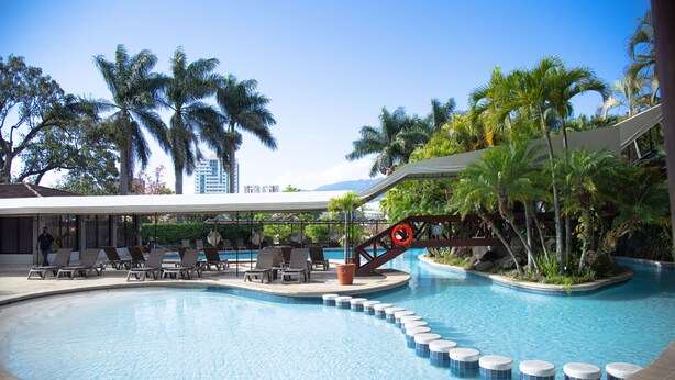 A swimming pool with lounge chairs and palm trees. - Barceló San José (San José)