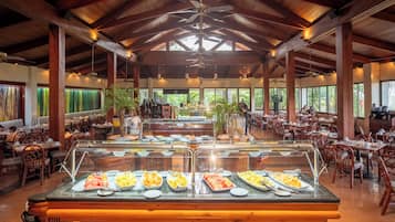 A spacious indoor dining area with a buffet counter, wooden ceiling beams, and large windows.