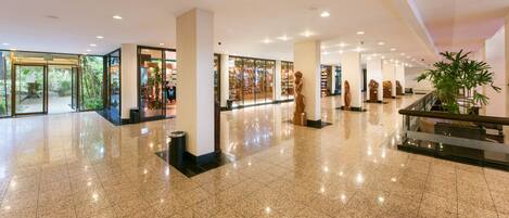 A spacious lobby with a polished floor, large pillars, and a glass storefront.