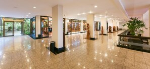 A spacious lobby with a polished floor, large pillars, and a glass storefront.