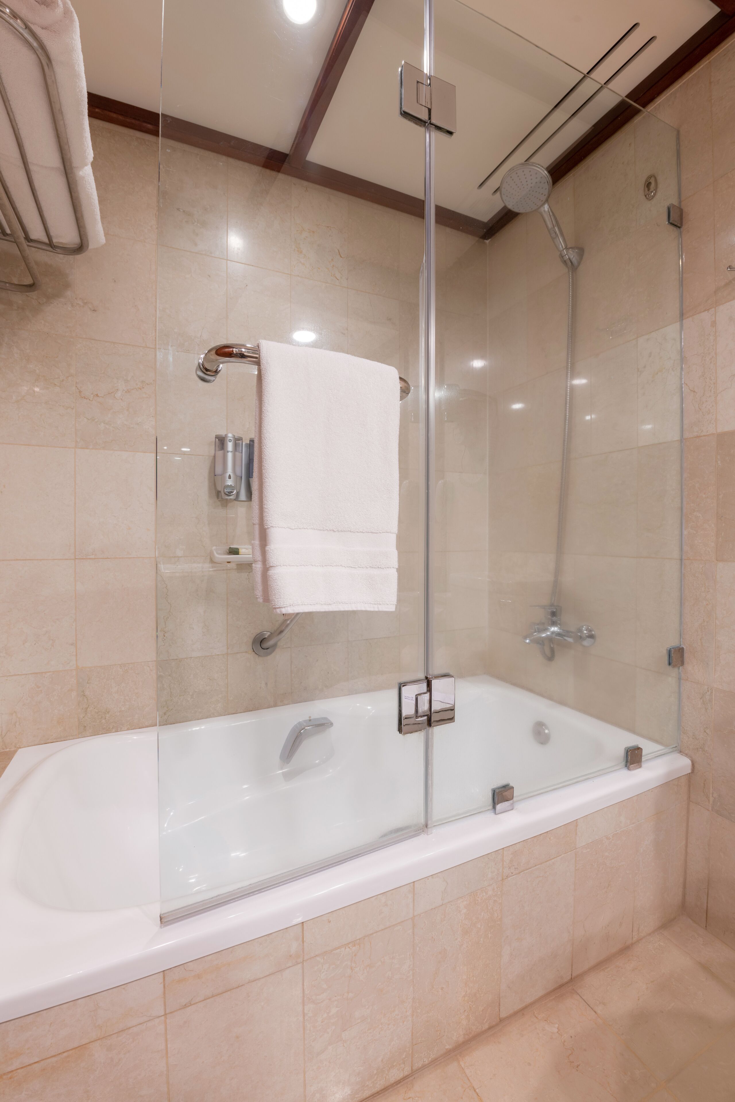 A modern bathroom with a glass-enclosed shower, a white bathtub, and a towel rack.