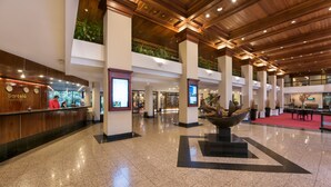 A spacious lobby with a high ceiling, polished tile flooring, and a reception desk. - Barceló San José (San José)