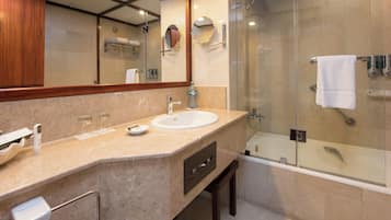 Un baño moderno con lavamanos de mármol, ducha con mampara de vidrio y un espejo grande.