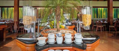 A buffet setup with a central palm tree, surrounded by various food containers and serving dishes.