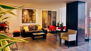 Una sala de estar moderna con un sofá de cuero, sillas rojas, una mesa de centro y arte abstracto en las paredes.