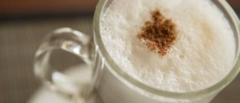 A clear glass cup with a frothy beverage and a sprinkle of spice on top.