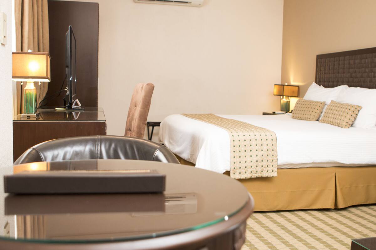 A hotel room with a bed, a desk, a chair, and a television.
