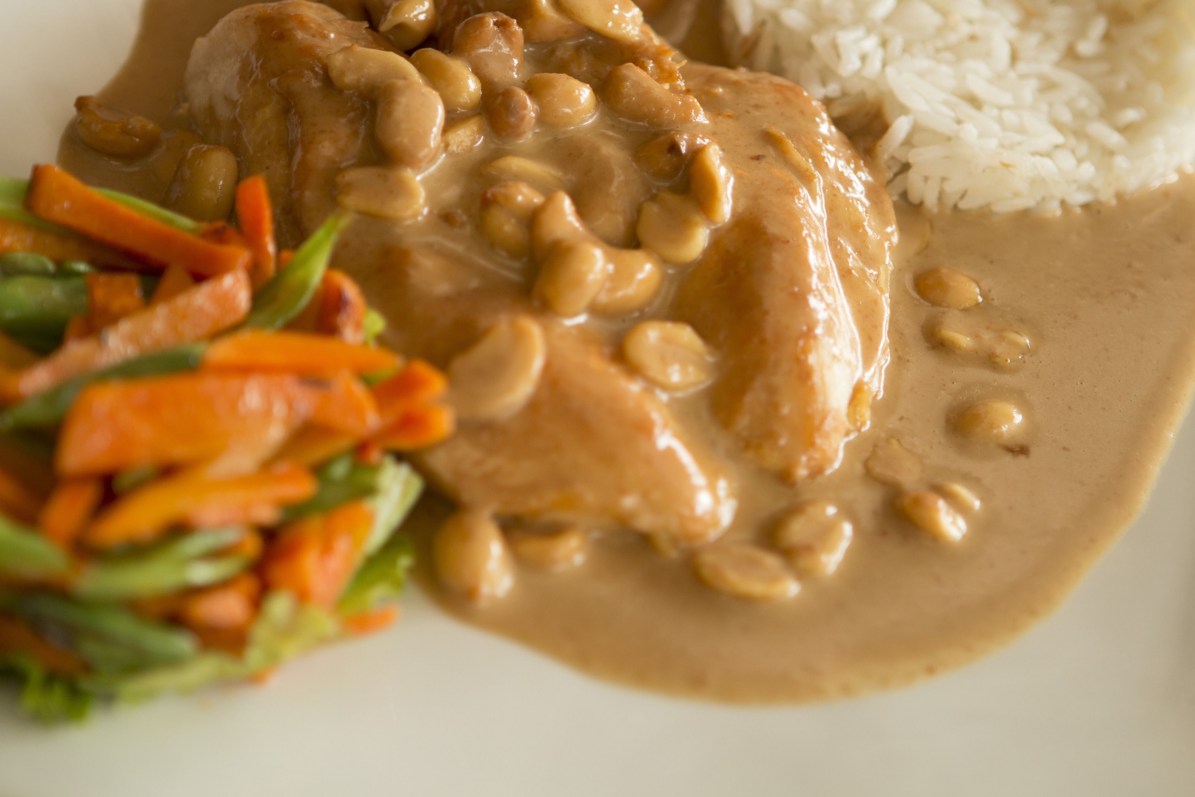 A plate of food with a creamy sauce, rice, and a side of vegetables.