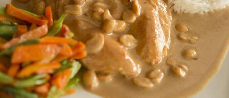 A plate of food with a creamy sauce, rice, and a side of vegetables.
