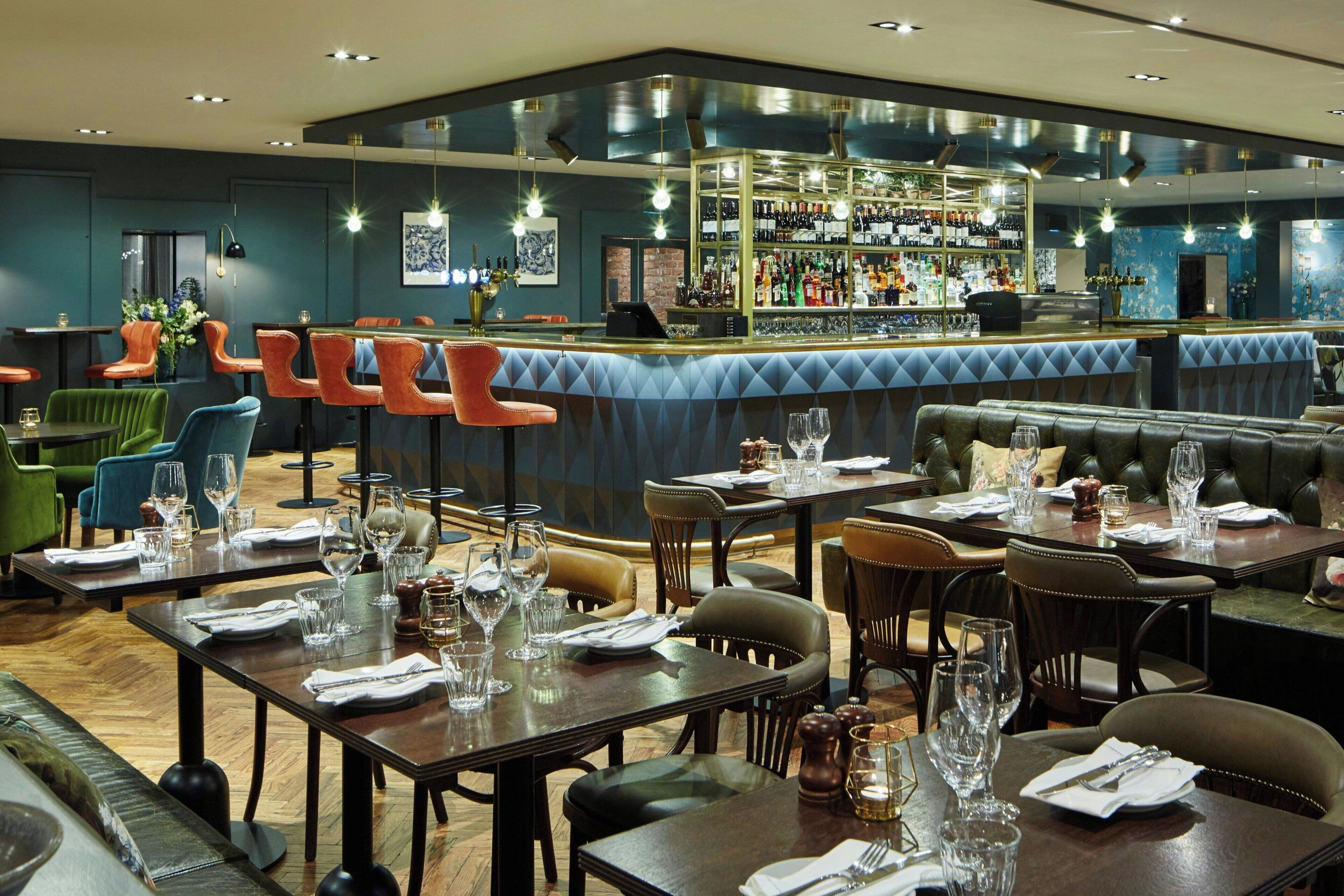 A restaurant with multiple dining tables, bar area, and bar stools.