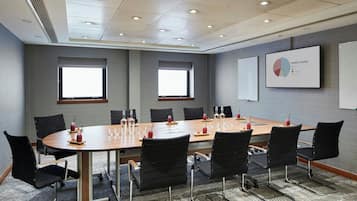 A conference room with a long table, black chairs, and a projector screen displaying a market share chart.
