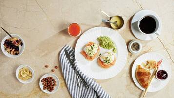 Una mesa de mármol con diversos alimentos y bebidas para el desayuno.