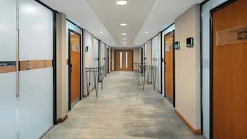 A hallway with glass partitions, wooden doors, and a carpeted floor.
