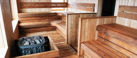 Una sauna de madera con bancos y una pileta de piedra.