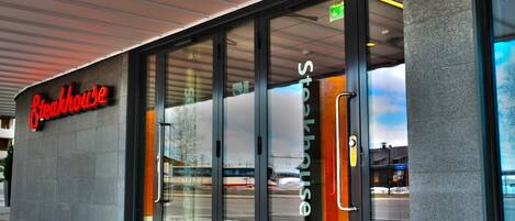 A Steakhouse with a glass entrance, red carpet, and a modern design.