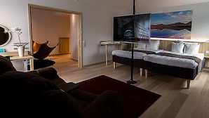 A modern hotel room with a bed, a desk, a chair, and a painting on the wall. - Grand Hotel Lapland (Gällivare)