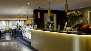 A hotel reception area with a counter, seating, and a view of the outside. - Grand Hotel Lapland (Gällivare)