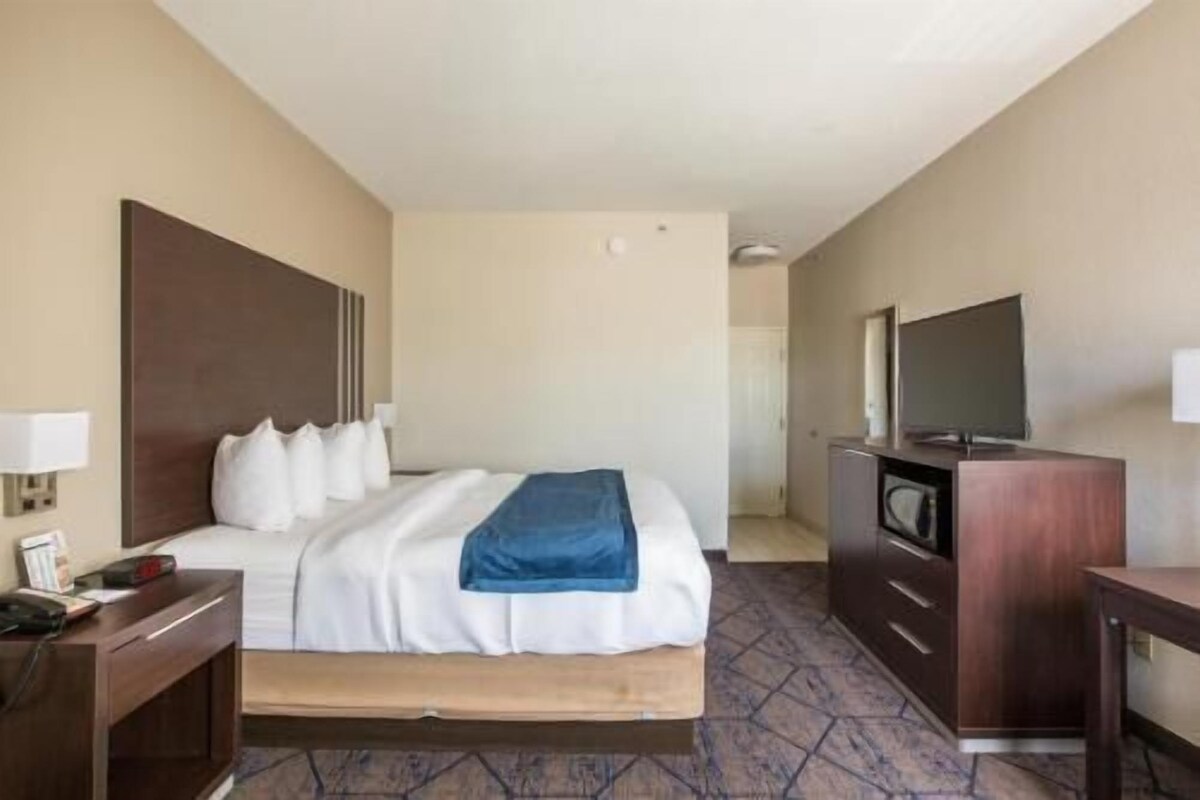 Une chambre d’hôtel comprenant un lit, un bureau, une commode, une télévision et une porte donnant sur une autre pièce.