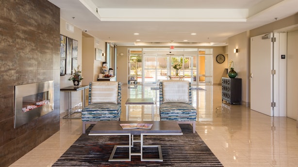 Eine geräumige Lobby mit modernem Design, inklusive einer Rezeption, einer Sitzecke mit gemusterten Stühlen und einer Wanddekoration.