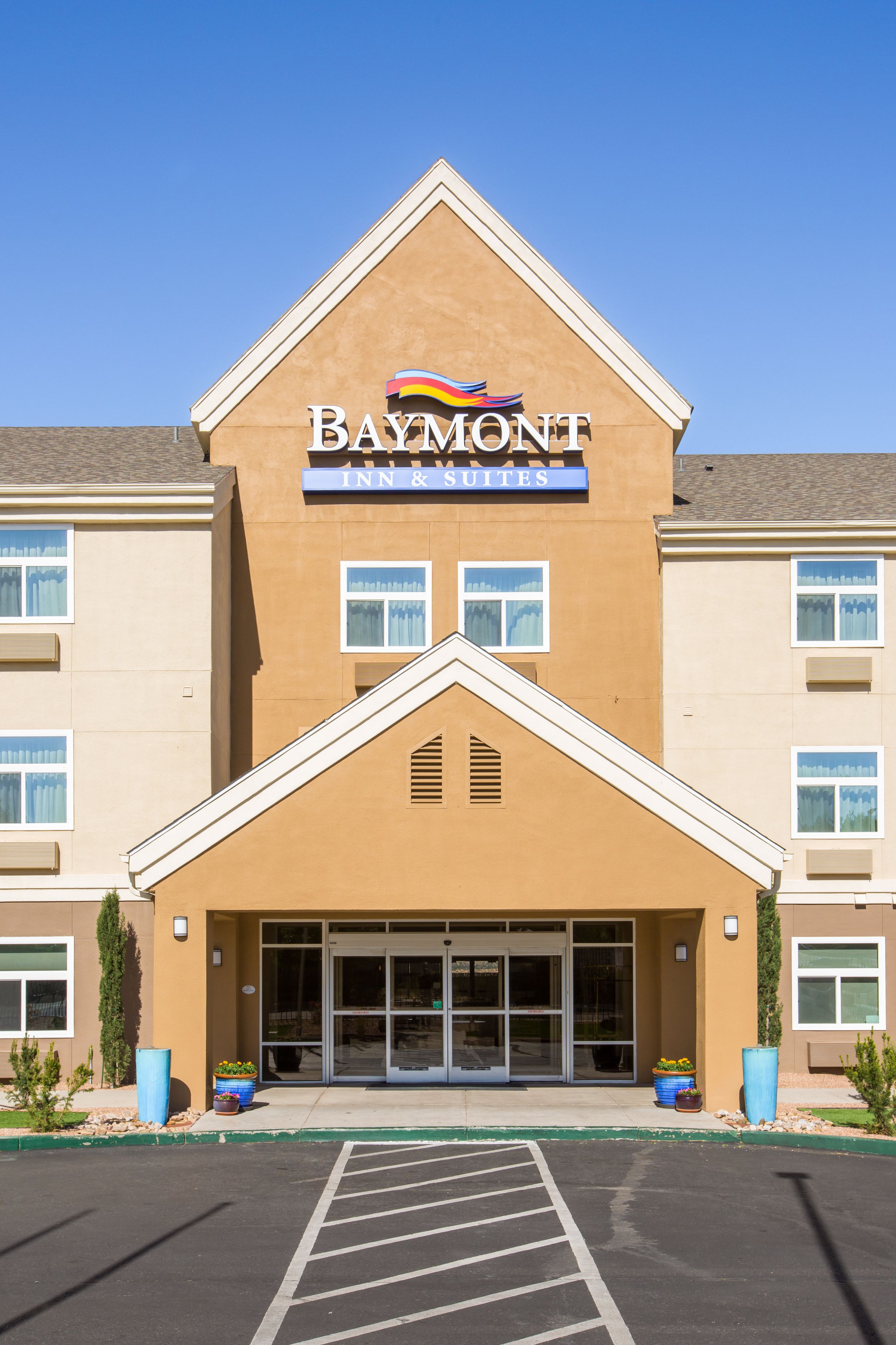 A Baymont Inn & Suites building with a prominent sign, large windows, and a parking lot.