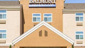 A Baymont Inn & Suites building with a prominent sign, large windows, and a parking lot.