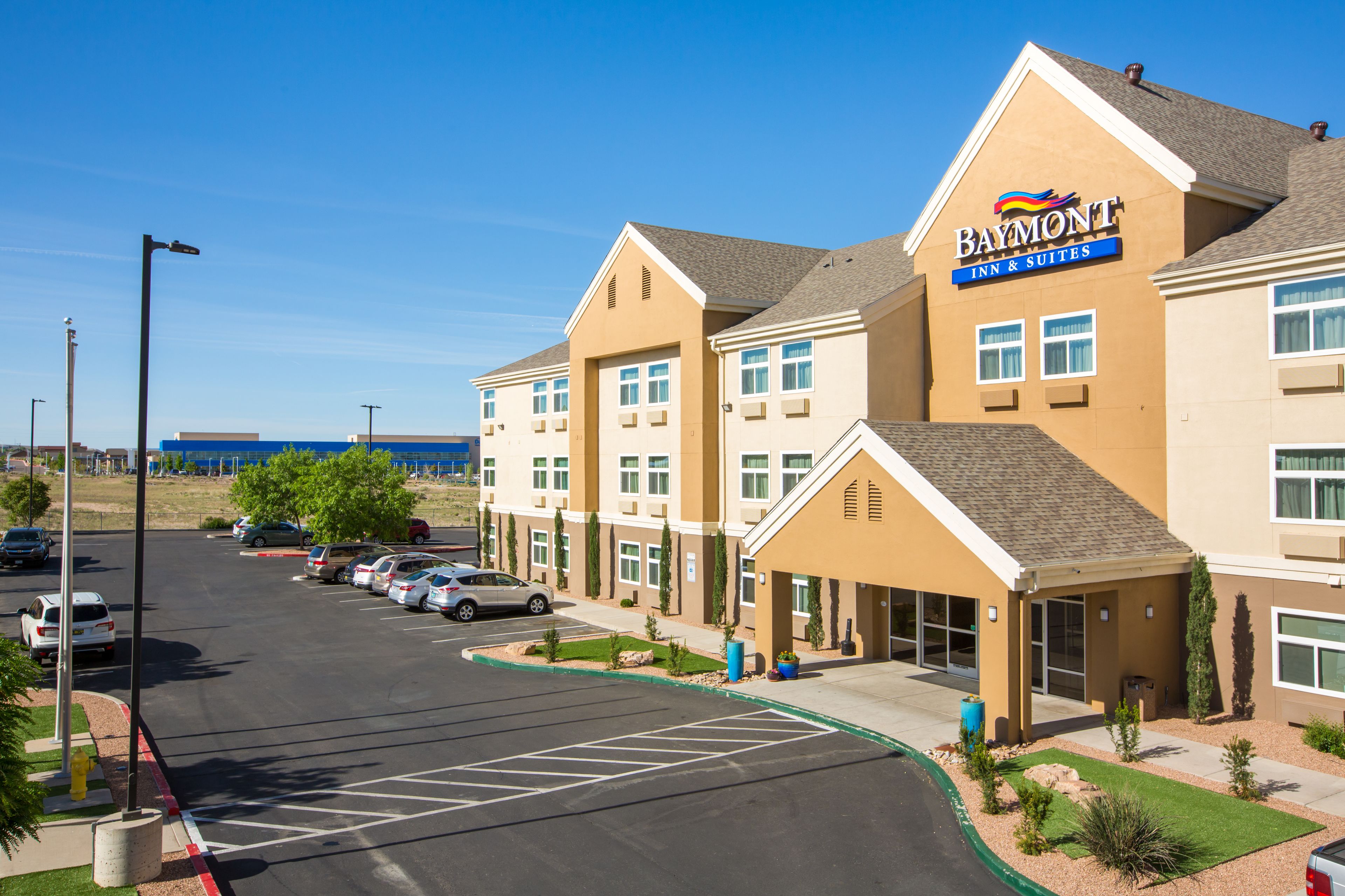 A Baymont Inn & Suites building with a parking lot and a clear blue sky.