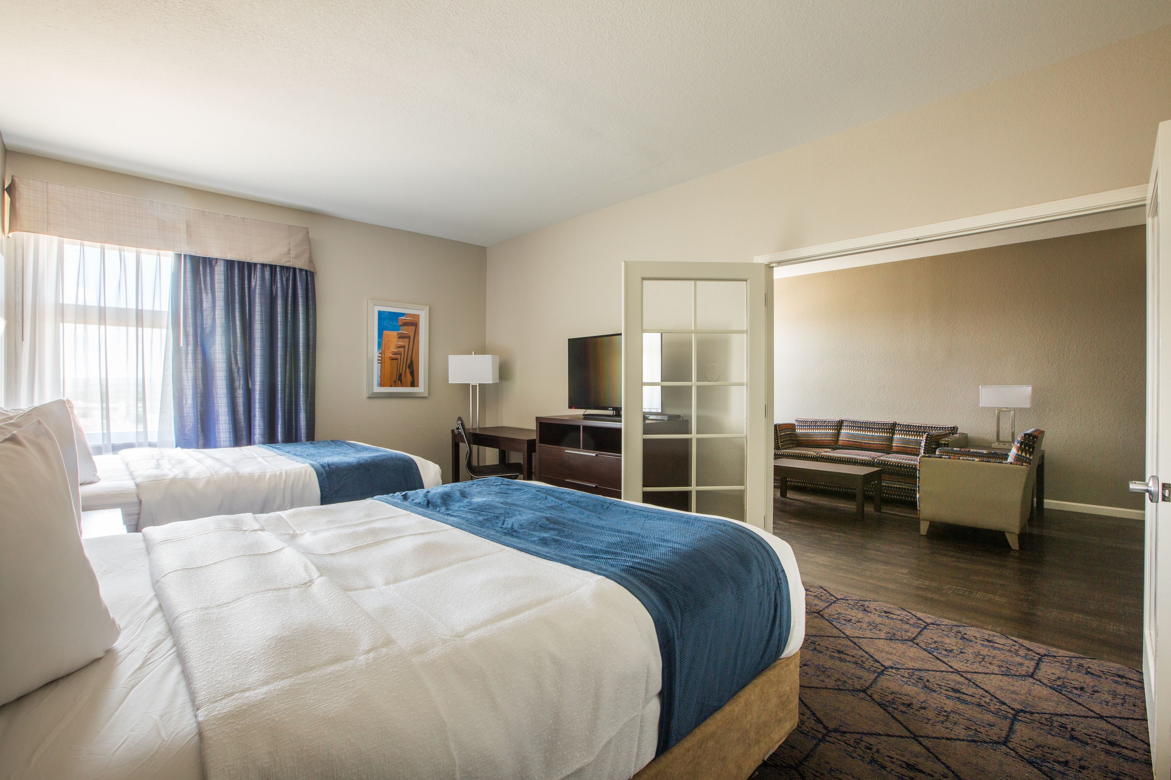 Habitación de hotel con dos camas, un escritorio, una silla, un sofá y un televisor.