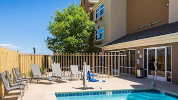A swimming pool with lounge chairs and a wooden fence.