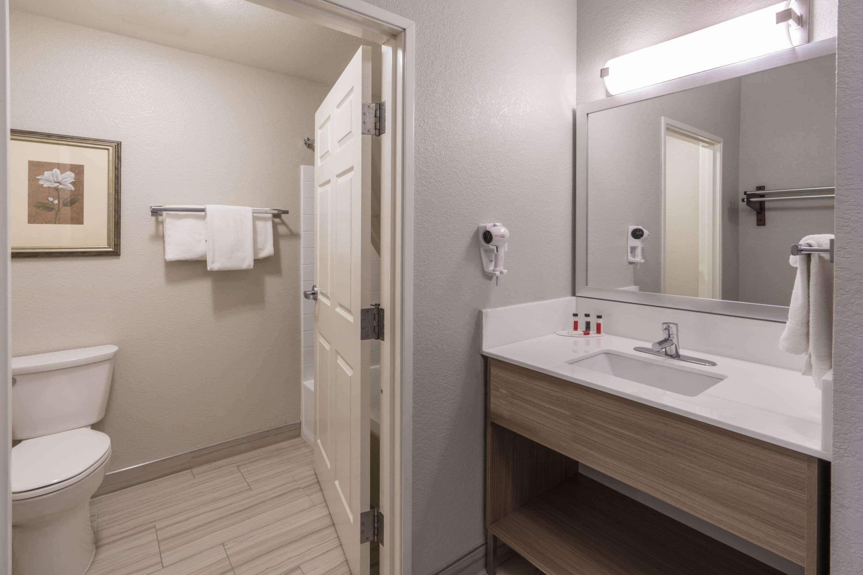 A bathroom with a toilet, a sink with a mirror, and a towel rack.