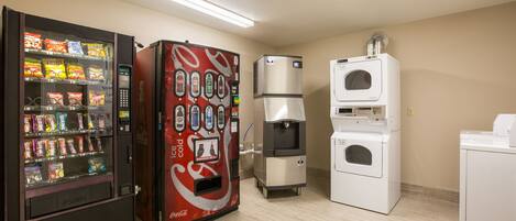 Zona de máquinas expendedoras con un refrigerador de Coca-Cola, una máquina de aperitivos y una lavadora-secadora.