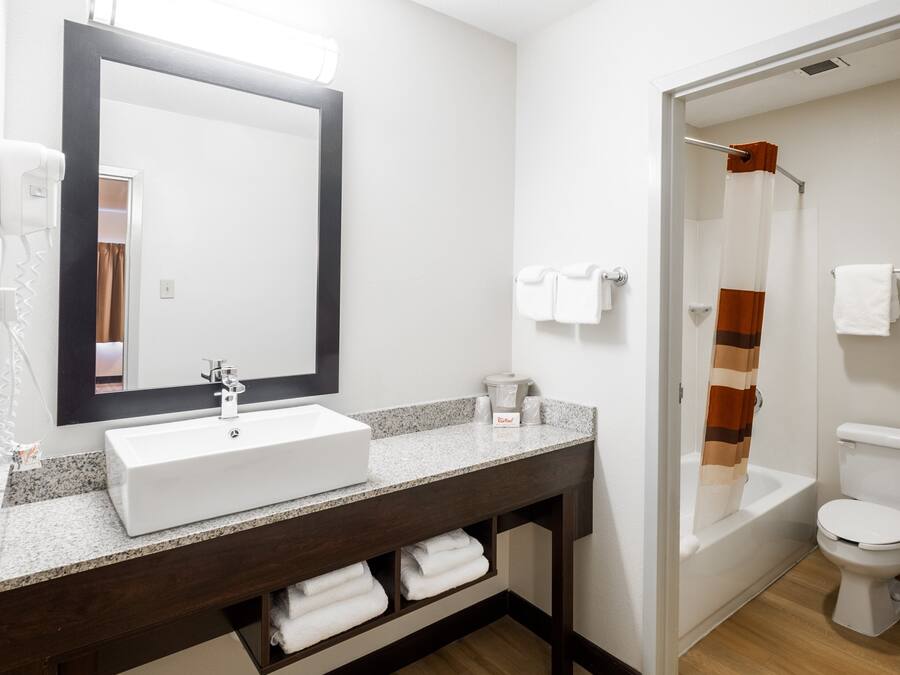 A bathroom with a white sink, dark wooden vanity, a large mirror, and a shower area.