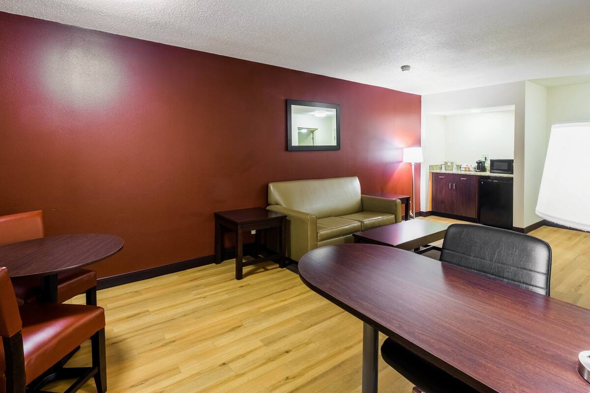 Habitación de hotel con suelo de madera, sofá, mesa de comedor y kitchenette.